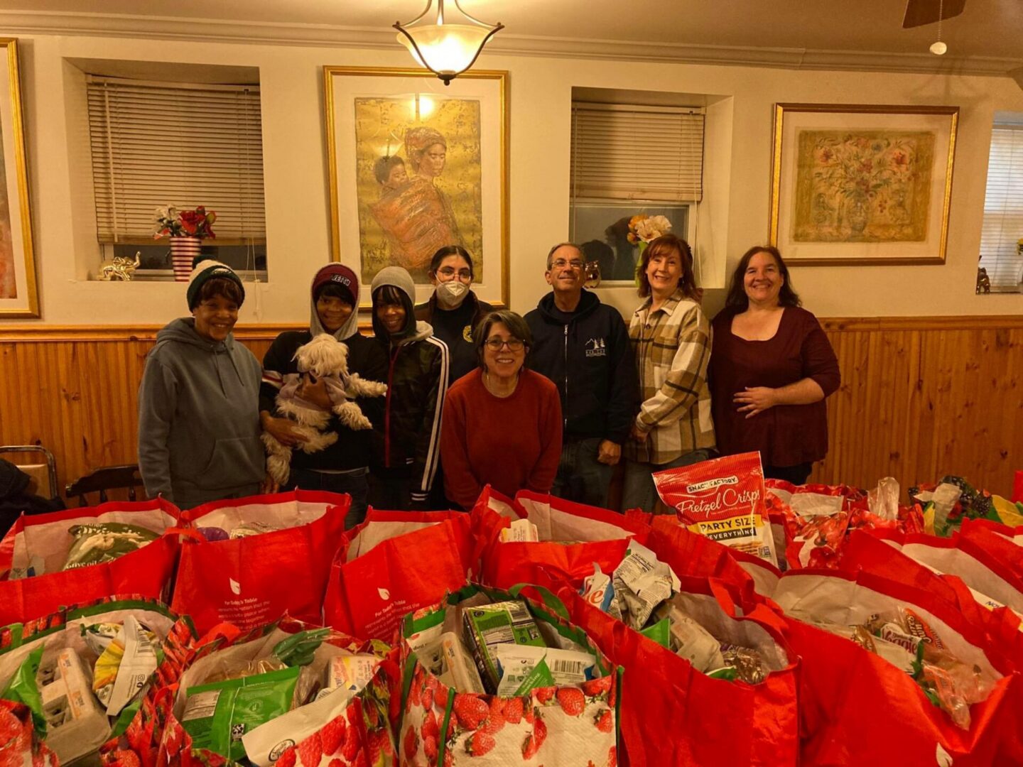 A picture of volunteers standing behind bags of groceries to give away.